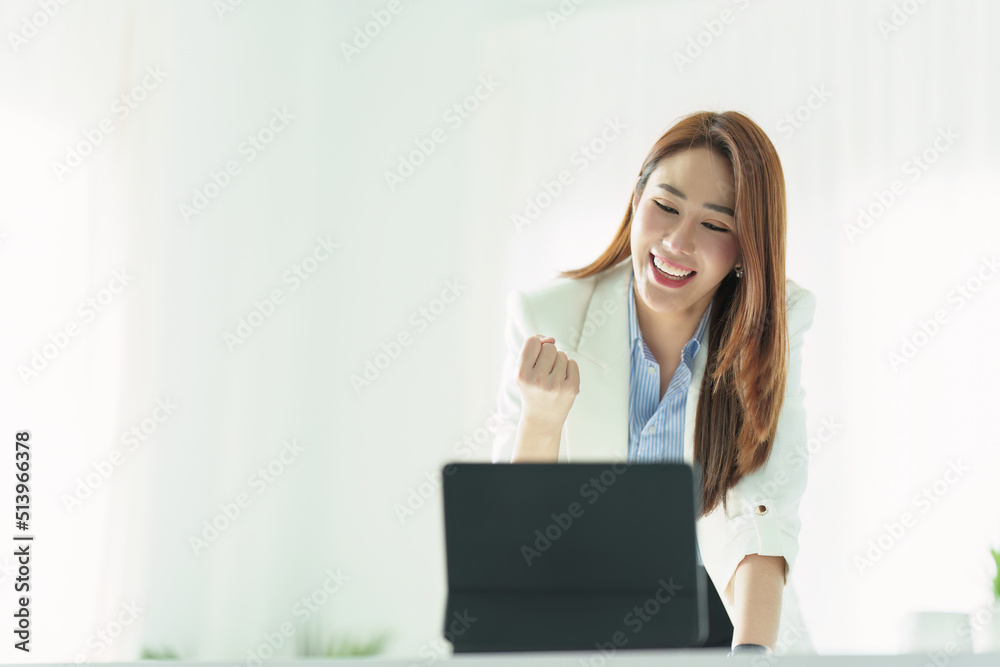 Portrait of a successful Asian businesswoman or business owner expressing excitement and joy using a tablet computer in the office Portrait of a successful Asian businesswoman or business owner expressing excitement and joy using a tablet computer in the office