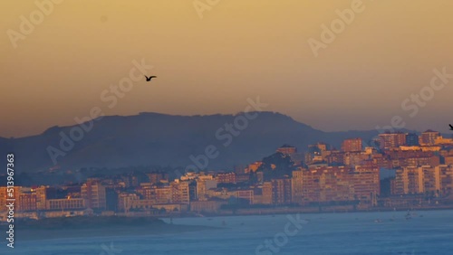 amazing shoot lateral panning from Somo beach where we see the bay of Santander during sunrise with its orange and purple colors and the buildings of Santander with a wonderful and unique light. photo