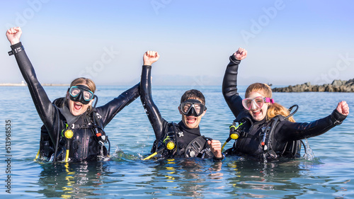 Happy scuba divers in the sea with their arms in the air jumping for joy