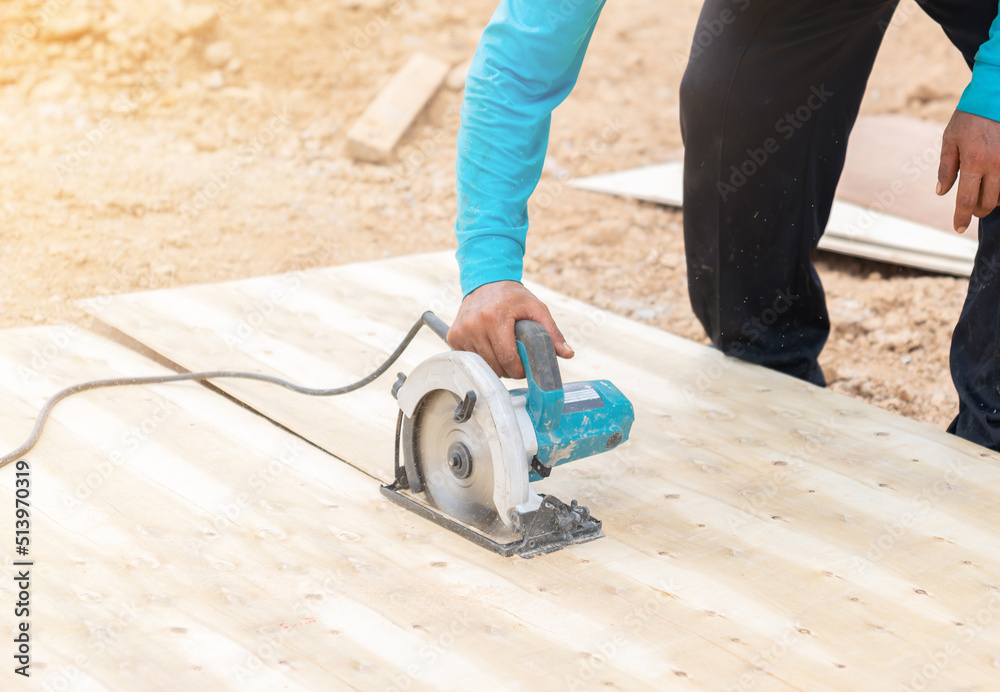 Worker use electric circular saw cutting plywood for concrete formwork . Worker use electric circular saw cutting plywood for concrete formwork .