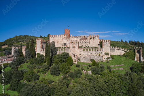 Soave castle aerial view Verona province, Italy. Ancient castle on a hill in Italy. Italian flag on the main tower of Soave Castle. View of Soave castle surrounded by vineyard plantations.