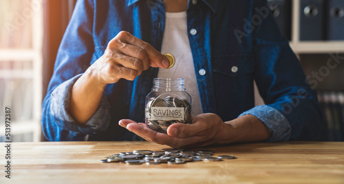 Woman puts a coin in a jar to save money for the future. after retirement and income, expenditure, savings and financial concepts