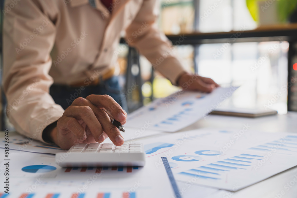 Businessmen hold graph pens and use a calculator for the company's improvement plan. Businessmen hold graph pens and use a calculator for the company's improvement plan.