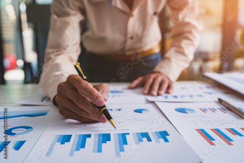 Businessmen hold graph pens and use a calculator for the company's improvement plan.