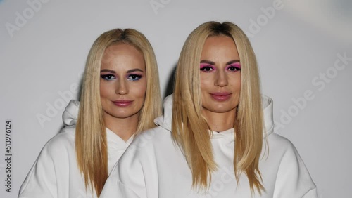 Two blondes in white clothes with bright makeup smile and open their eyes,white background,close-up