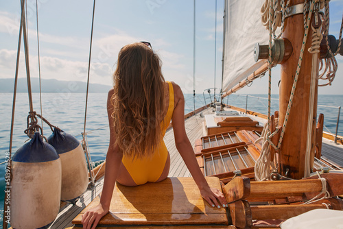 Fotografie, Obraz Woman in yellow swimwear looking at the ocean view sitting on a boat