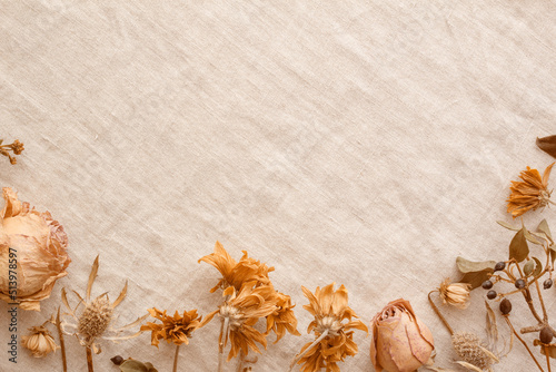 Decorative frame with orange-tinged dried flowers in vintage style and burlap background