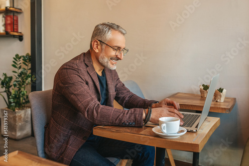 Man sitting sideways to camera working on laptop photo