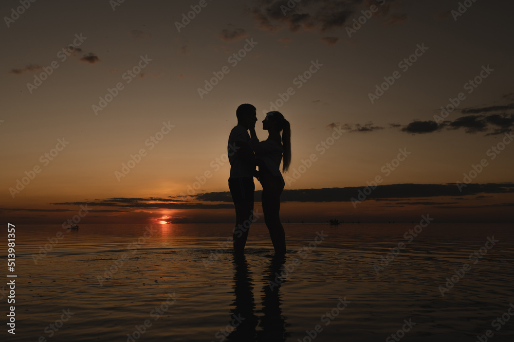 Romantic couple on the background of sunset near the ocean. Sunset walk along the ocean Romantic couple on the background of sunset near the ocean. Sunset walk along the ocean