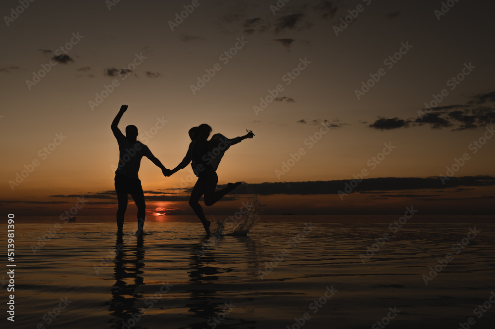 Romantic couple on the background of sunset near the ocean. Sunset walk along the ocean Romantic couple on the background of sunset near the ocean. Sunset walk along the ocean