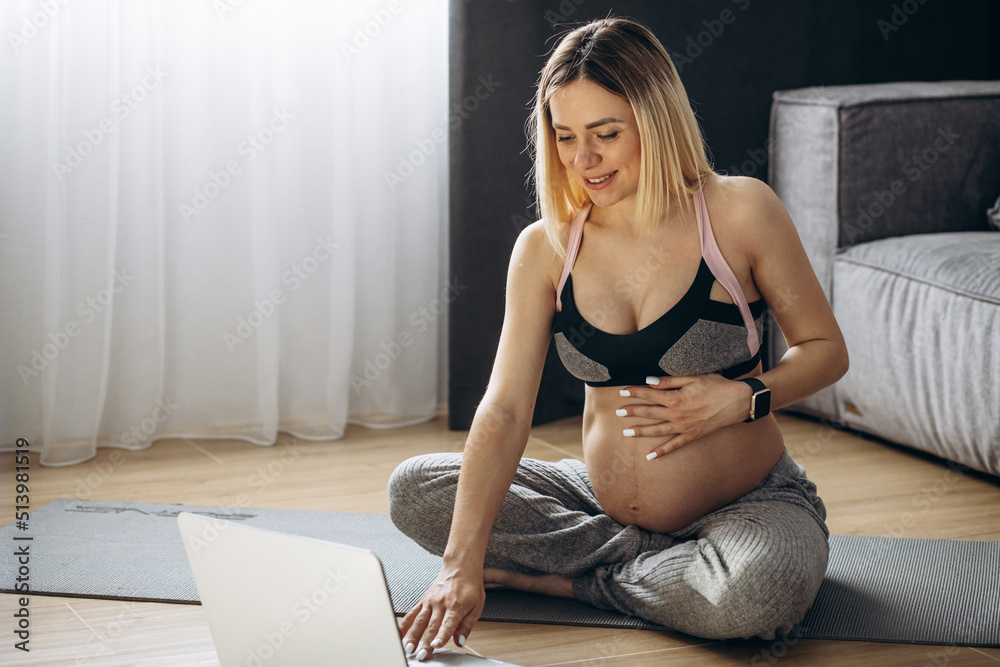Pregnant woman practicing yoga at home on the mat