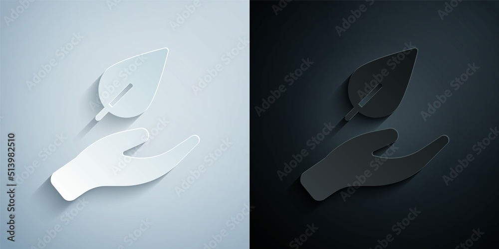 Paper cut Hand hold a leaf of the plant icon isolated on grey and black background. Care nature. Leaf shoots with environmental protection. Paper art style. Vector