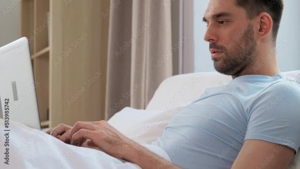 people, technology and remote job concept - man with laptop computer lying in bed at home bedroom people, technology and remote job concept - man with laptop computer lying in bed at home bedroom