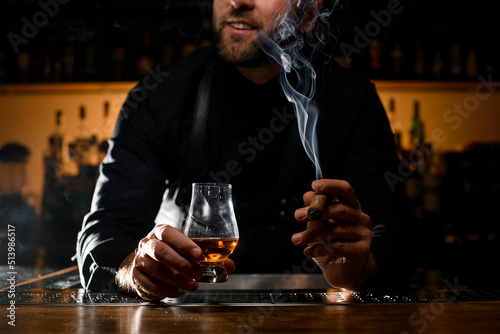 glorious view of male hands holding a glass of alcoholic drink and smoking cigar
