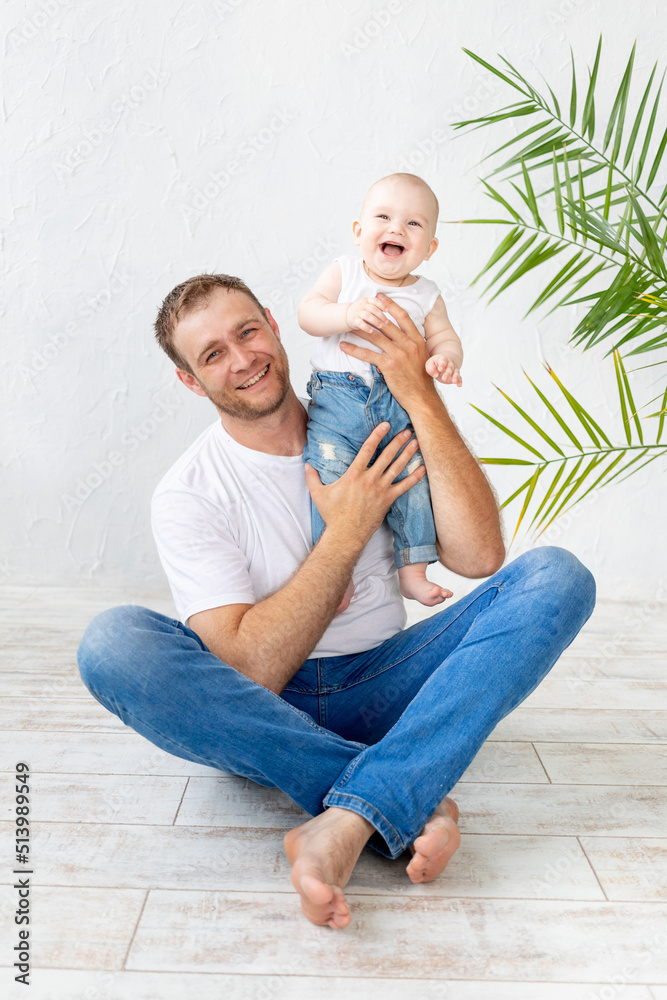 Fototapeta premium dad with baby son in his arms laughing on a white background, happy fatherhood and family, father's day