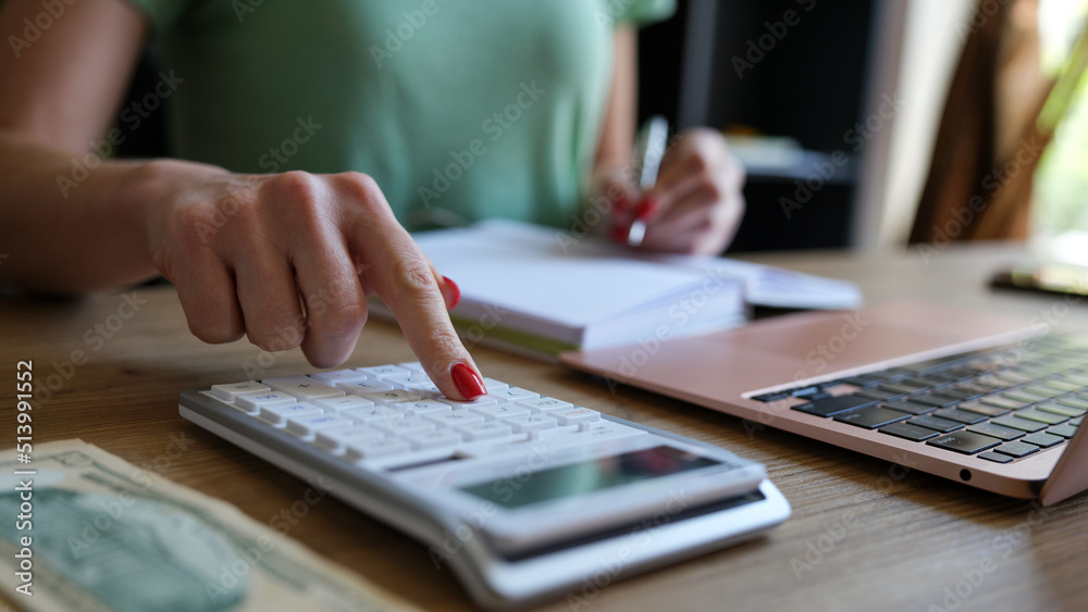 Woman hand using a calculator and letter makes note with cost calculation in home office Woman hand using a calculator and letter makes note with cost calculation in home office