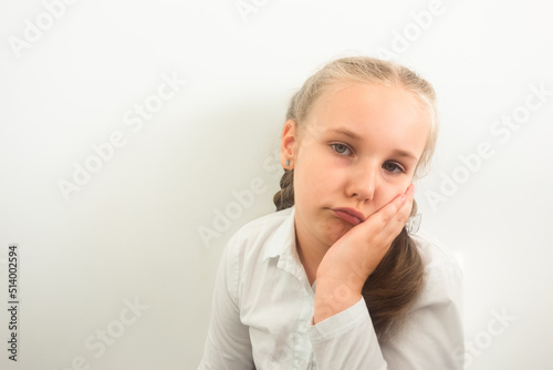 Little girl wearing white shirt is having toothache or feeling sad and worried