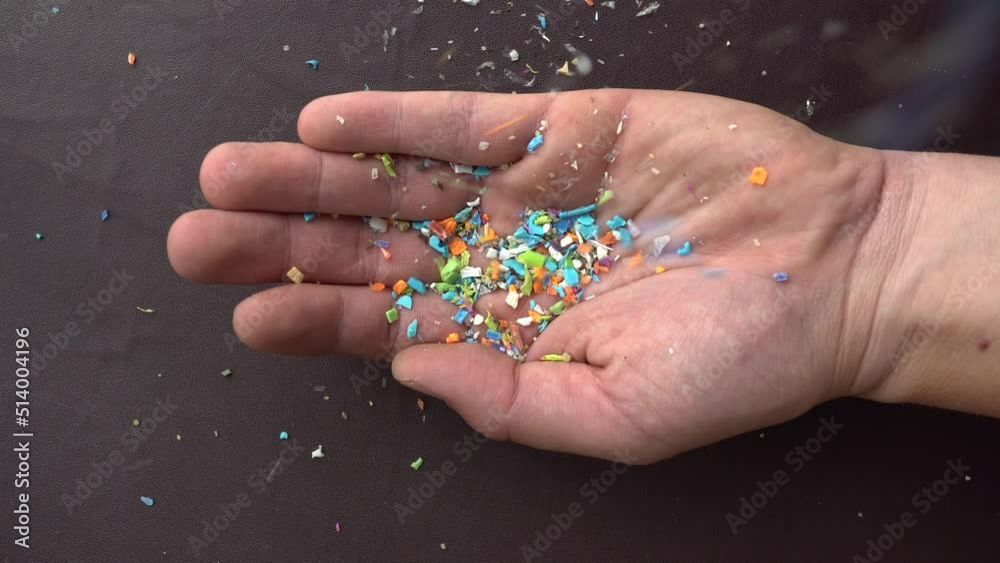 Close-up on micro plastic particles falling in a person hand. The concept for water pollution and global warming. Macro shot on a bunch of microplastics that cannot be recycled Close-up on micro plastic particles falling in a person hand. The concept for water pollution and global warming. Macro shot on a bunch of microplastics that cannot be recycled