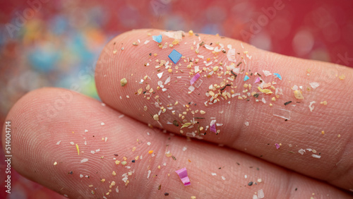 Micro plastic particles on a human finger for scale. Concept for water pollution and global warming. Macro shot on a bunch of microplastics that cannot be recycled photo
