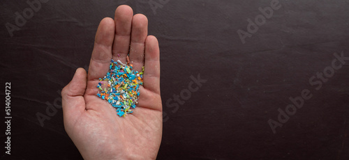 Close-up of micro plastic particles in a person hand with room for text on the righ. The concept for water pollution and global warming.  Macro shot on a bunch of microplastics that cannot be recycled photo