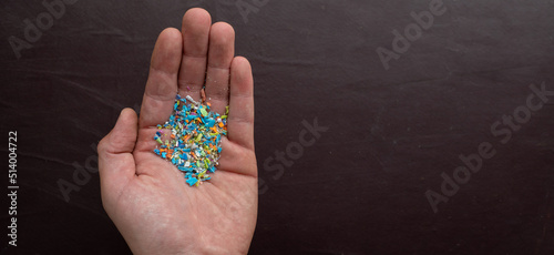 Close-up of micro plastic particles in a person hand with room for text on the righ. The concept for water pollution and global warming.  Macro shot on a bunch of microplastics that cannot be recycled