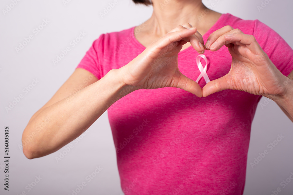 White female model with pink ribbon hold fingers in heart shape