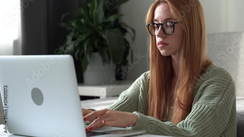 Beauty young woman typing on laptop, sitting on sofa at home. office chat, virtual training concept. Self-isolation at COVID-19 Pandemic 4k footage