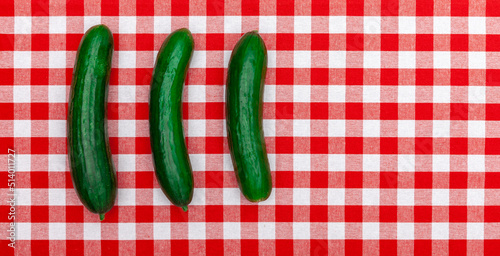 Drei Grüne Gurken auf rot weiß karierter Tischdecke