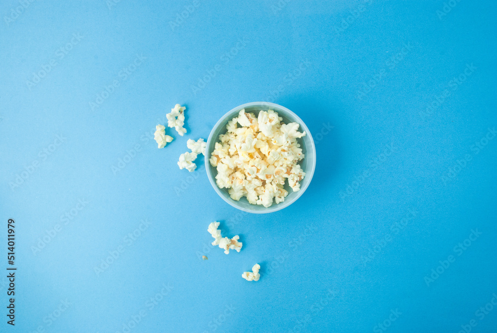 Popcorn in a blue bowl on a blue background