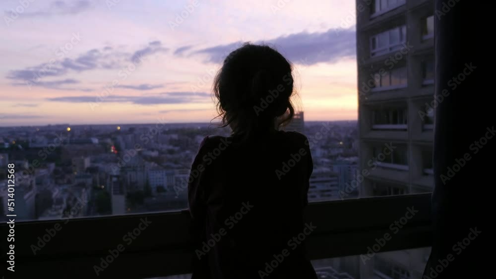 A child watches the sunset from the window of his building, in Paris, France A child watches the sunset from the window of his building, in Paris, France