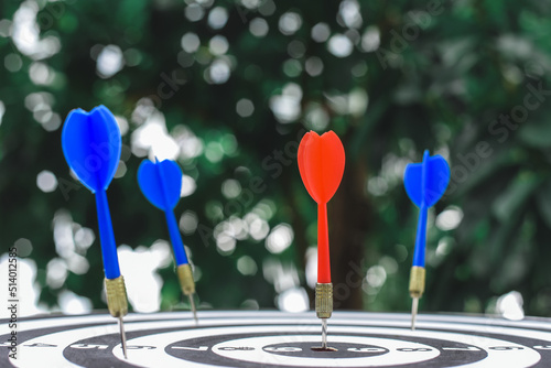 Red dart arrow hit the center target of dartboard and blue dart arrow hit out of center with blur background. Target business or market goals concept