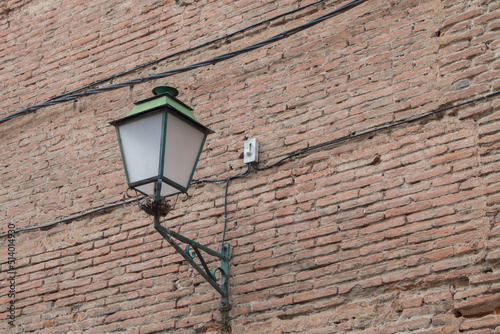 lantern on a brick wall in a street in Alcalá de Henares, province of Madrid. Spain