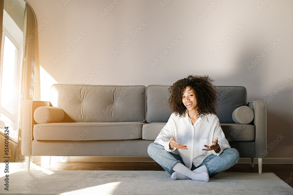 Portrait of a beautiful young woman with black curly hair. African american girl smiling at home interior. People, lifestyle, beauty concept Portrait of a beautiful young woman with black curly hair. African american girl smiling at home interior. People, lifestyle, beauty concept