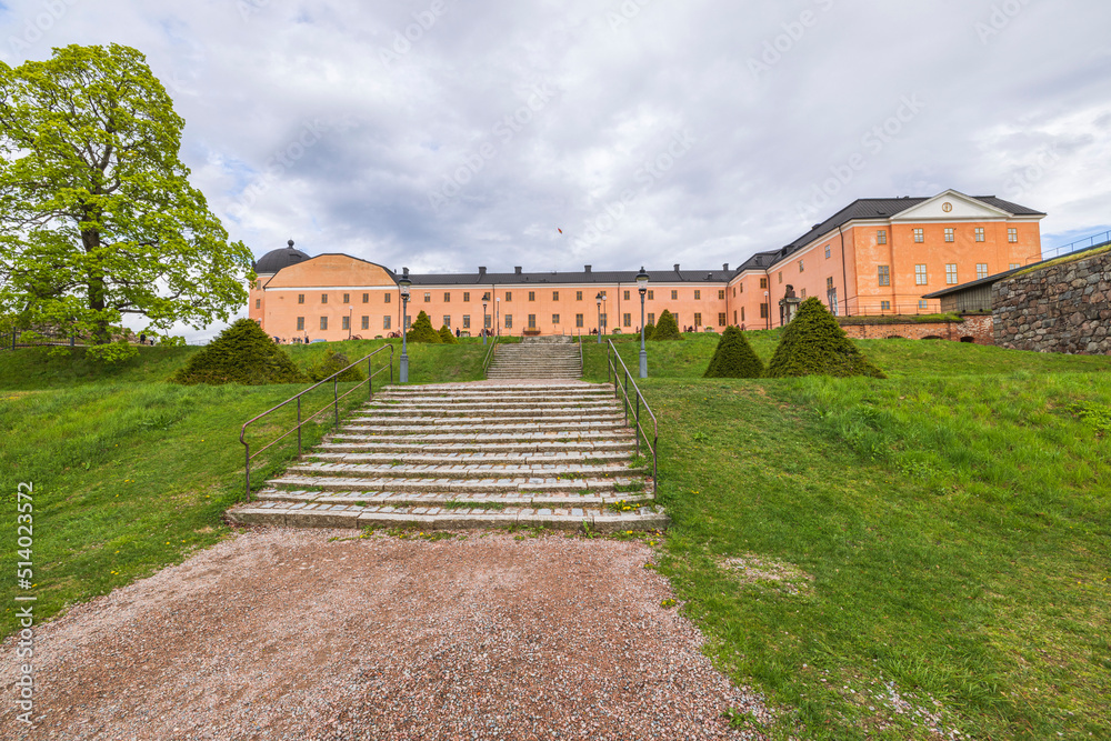 Beautiful exterior of Royal Palace with green lawn and staircase leading up to building in foreground. Sweden.