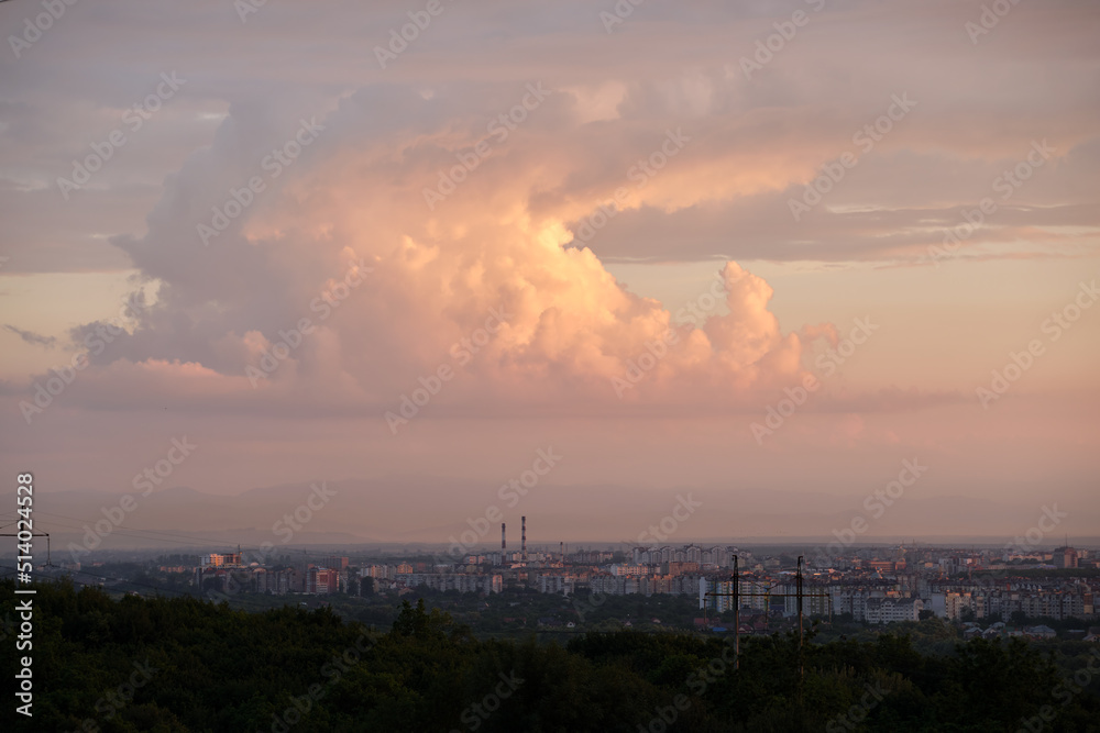 Evening landscape with bright sunset over distant city high rise buildings