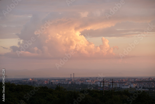 Evening landscape with bright sunset over distant city high rise buildings