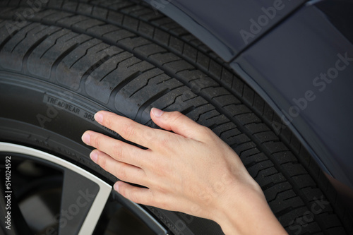 Female driver hands inspecting wheel tire of her new car. Vehicle safety concept © bilanol