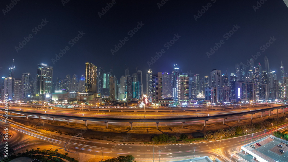 Panorama of Dubai Marina skyscrapers and Sheikh Zayed road with metro railway aerial night timelapse, United Arab Emirates