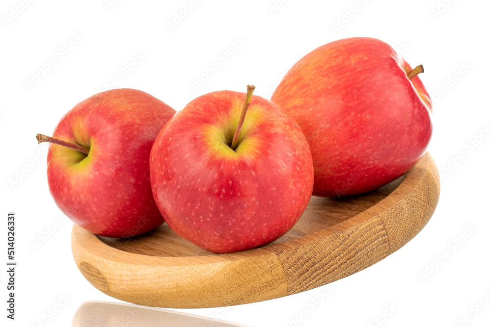 Three juicy red apples on a wooden tray, close-up, isolated on a white background. Three juicy red apples on a wooden tray, close-up, isolated on a white background.