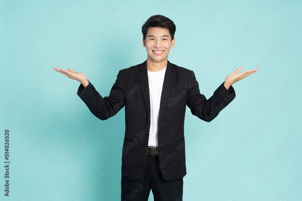 Happy young Asian businessman presenting or showing open hand palm with copy space for product isolated on green background Happy young Asian businessman presenting or showing open hand palm with copy space for product isolated on green background