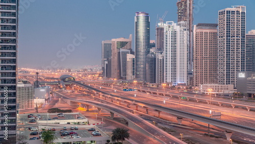 Dubai Marina skyscrapers and Sheikh Zayed road with metro railway aerial night to day timelapse, United Arab Emirates