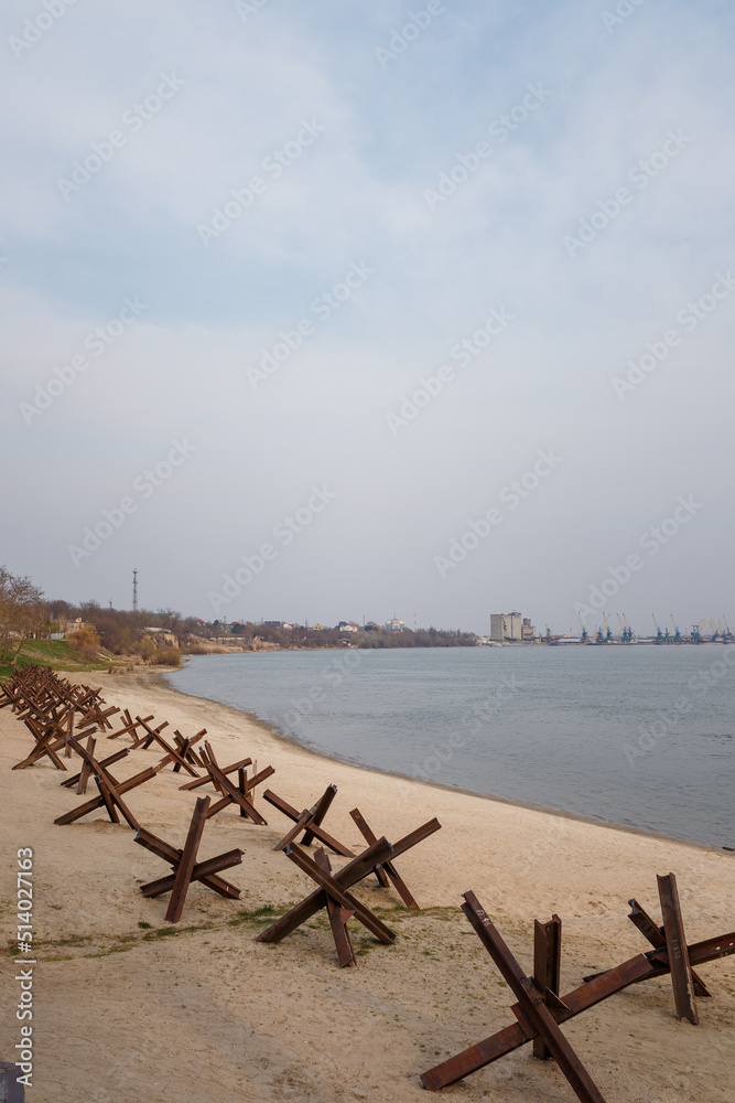 Military anti-tank czech hedgehogs on river bank. Metallic barricade or obstacle for defense. War in Ukraine 2022. Russian aggression Military anti-tank czech hedgehogs on river bank. Metallic barricade or obstacle for defense. War in Ukraine 2022. Russian aggression