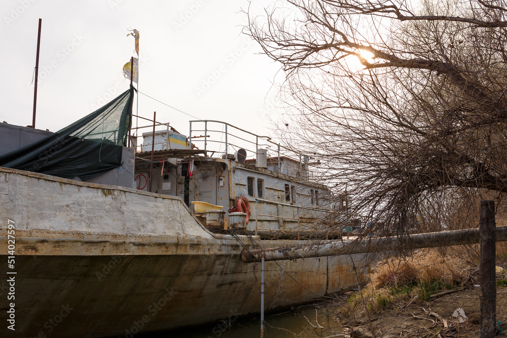 Rusty old ship or boat with ukrainian flag colors at river bank Rusty old ship or boat with ukrainian flag colors at river bank