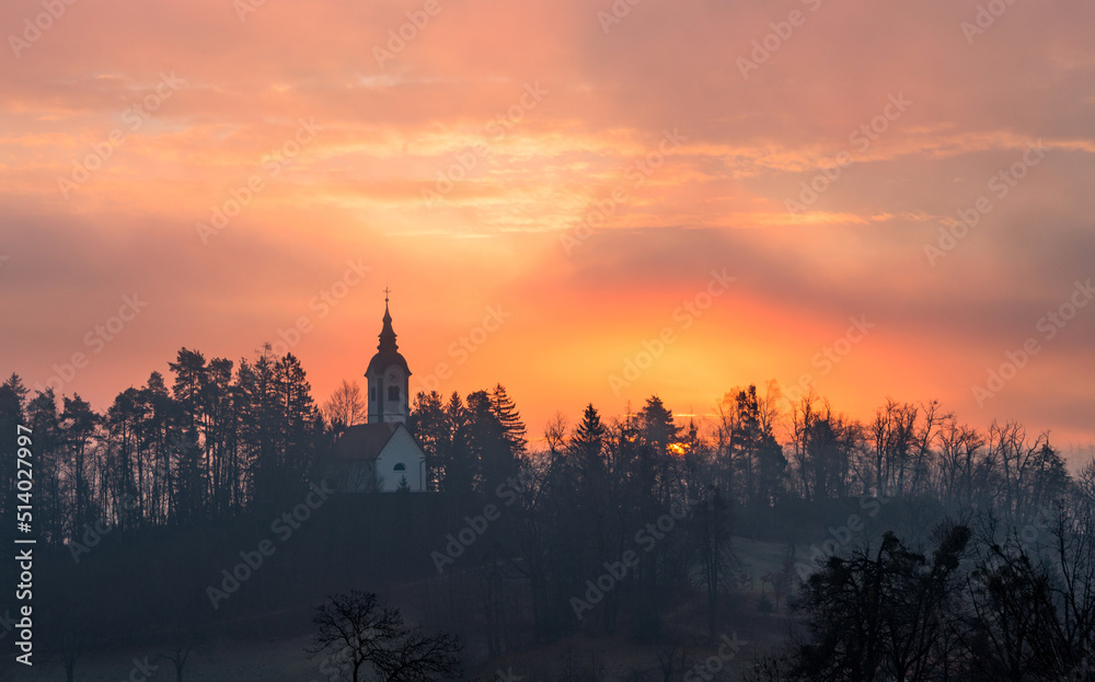 Vivid sunrise over the church on a misty morning on Bled