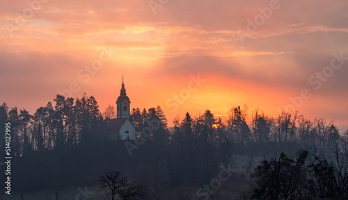 Vivid sunrise over the church on a misty morning on Bled