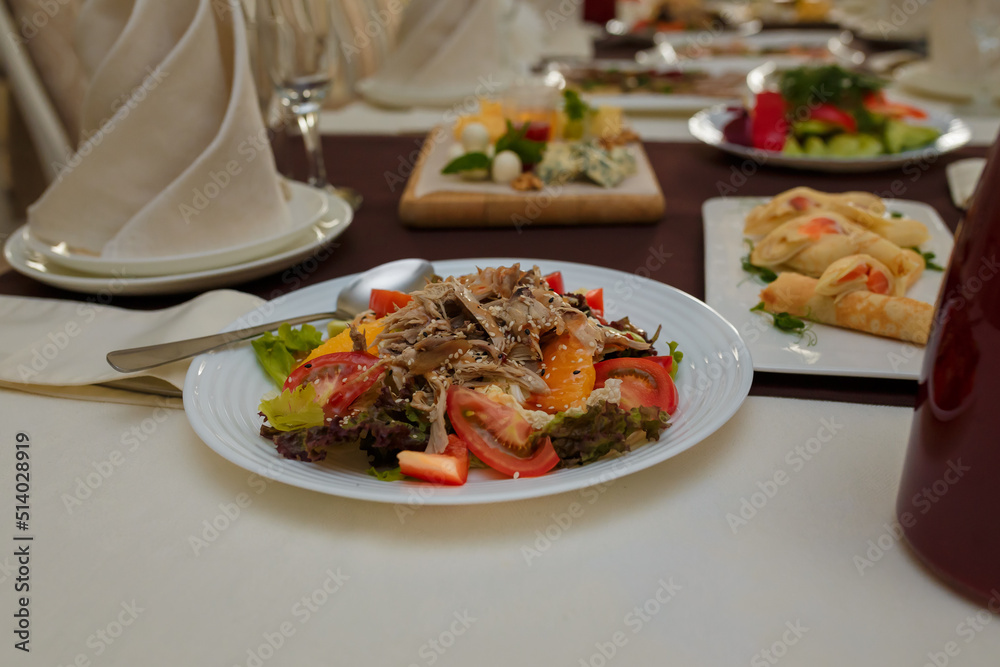 Festive table with appetizers. Meat and vegetable salad, pancakes with caviar and microgreen. Empty glasses, plates for guests Festive table with appetizers. Meat and vegetable salad, pancakes with caviar and microgreen. Empty glasses, plates for guests