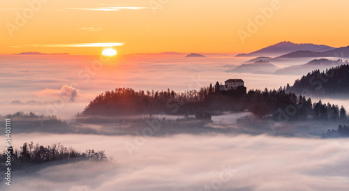 Church and villages hiding in the early morning fog. A misty sunrise in the countryside.