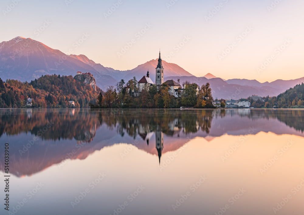 Obraz premium Lake Bled at Sunrise. Church, castle and the mountains are basking in the morning sun