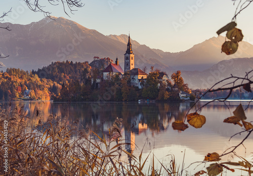 Lake Bled at Sunrise. Church, castle and the mountains are basking in the morning sun
