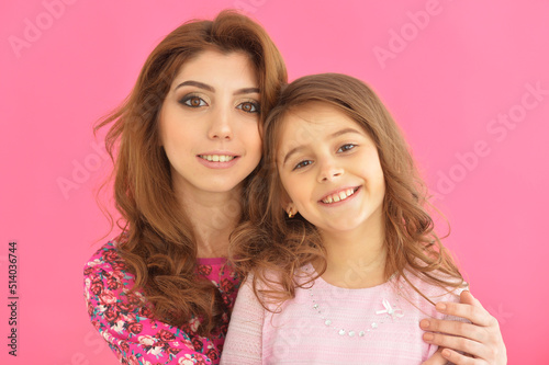two beautiful girls hugging on a pink background